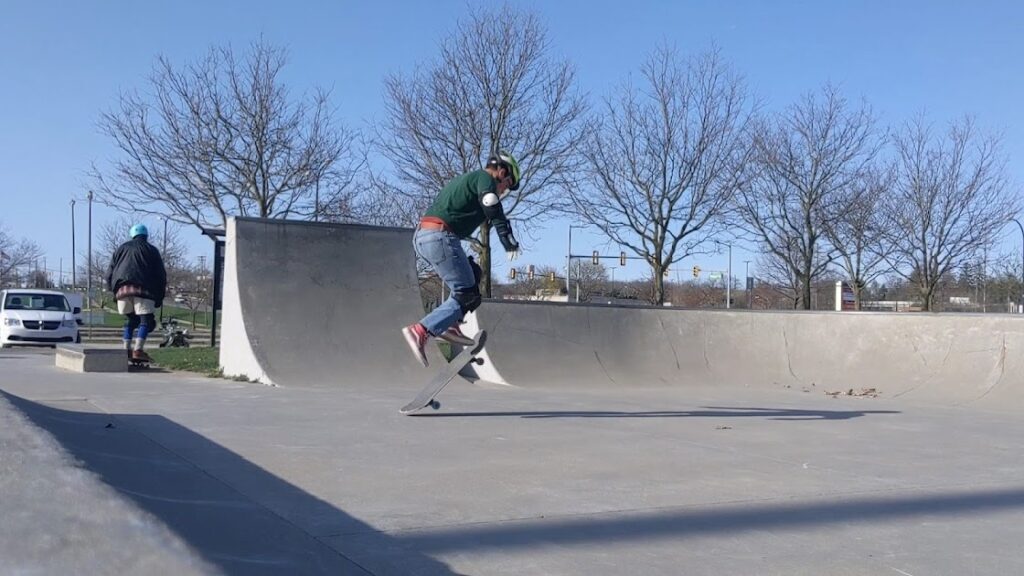 A dad wearing a lot of pads to the skatepark