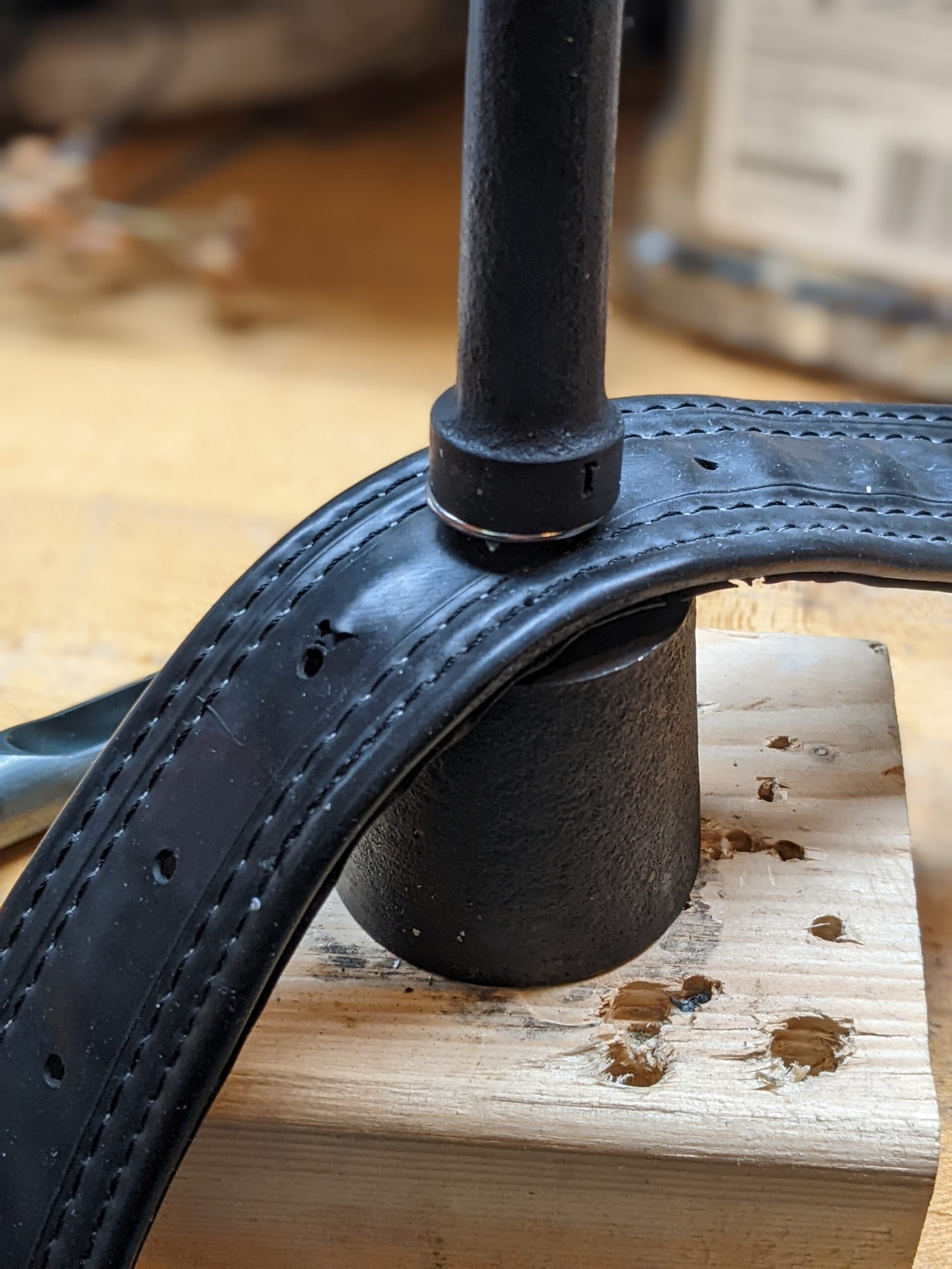 the belt is sandwiched between two pieces of a grommet setter and die