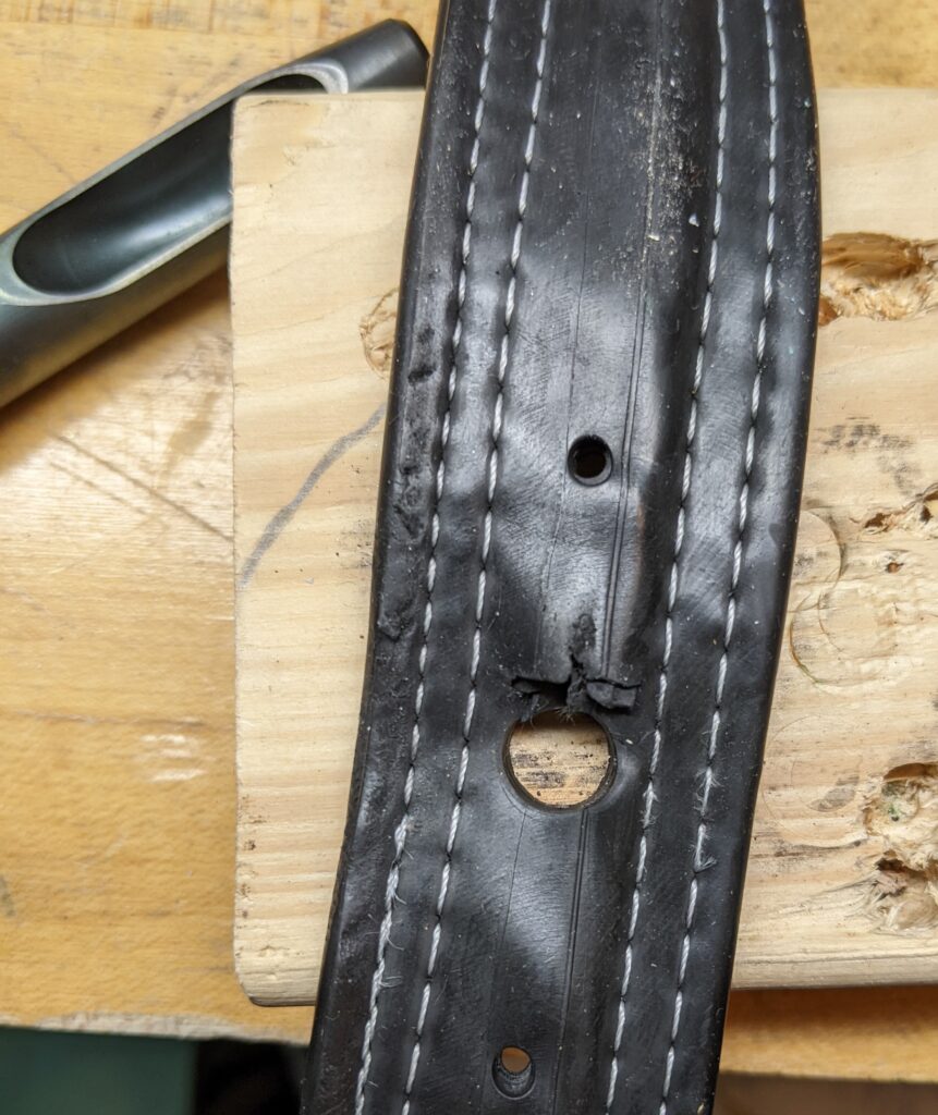 the black belt on a scrap of wood on a wood workbench, with a clean large hole punched in it